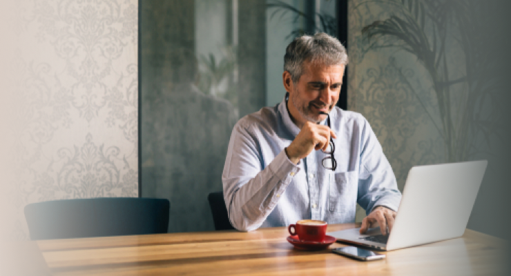 Mature man reading a financial publication on his laptop