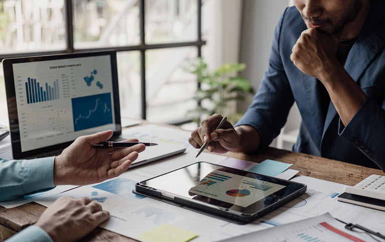 Two men analyzing charts and distributions.
