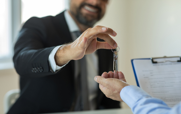An image of a business owner handing over his keys to a new business owner.
