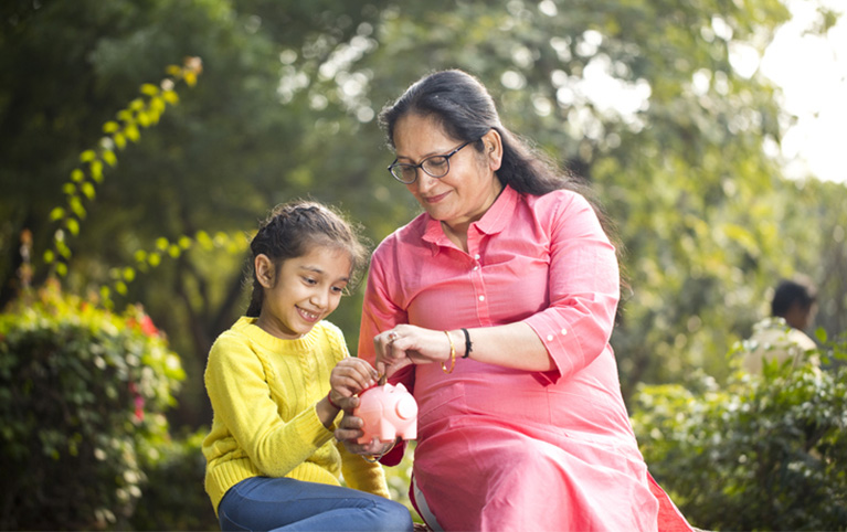 Grandmother putting coins in her granddaughter's piggy bank. Title: Giving while living – an introduction