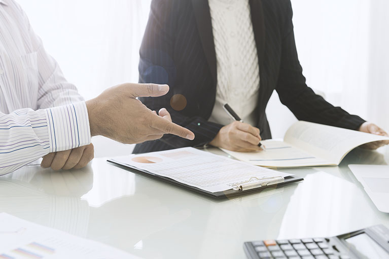 Two person around a table with a document on the table