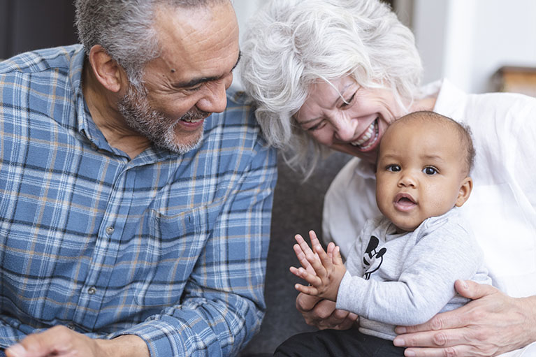 An old man and an old woman laughing with a little child