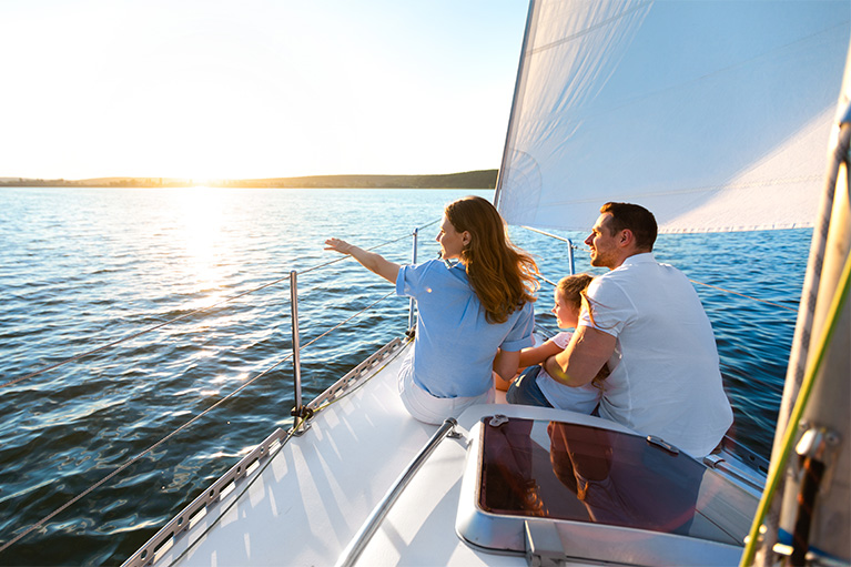 Couple sitting with their baby on the edge of a boat.