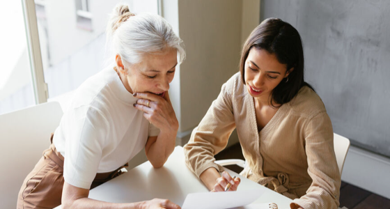 Two women looking at papers on a table.