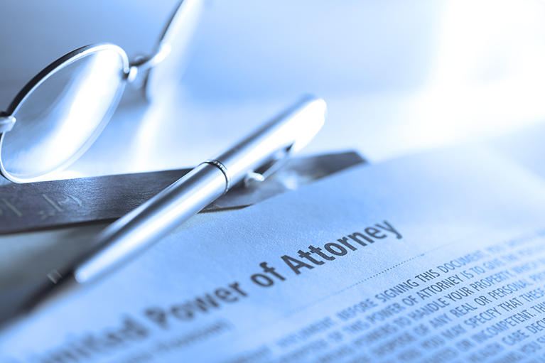 Power of Attorney Document beside a pen and a pair of glasses