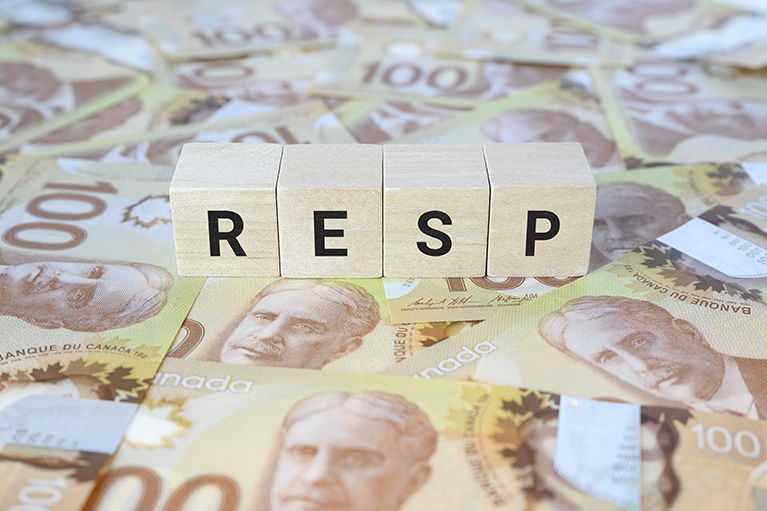 RESP (Registered Education Savings Plan) on wooden blocks and Canadian 100 dollar bills.