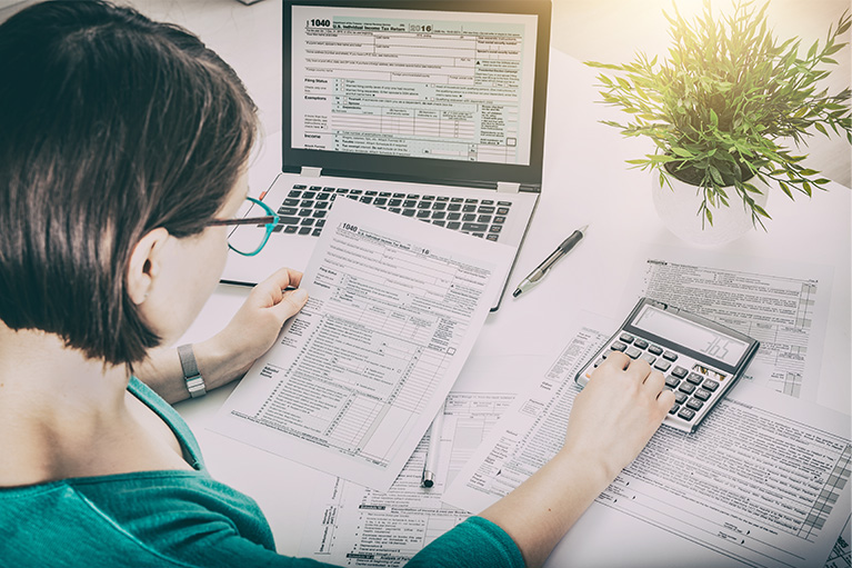 women sitting at desk with tax filing forms and laptop