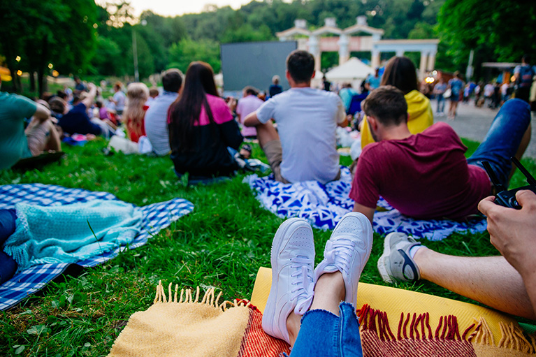 people sitting on blankets in a park watching outdoor movie