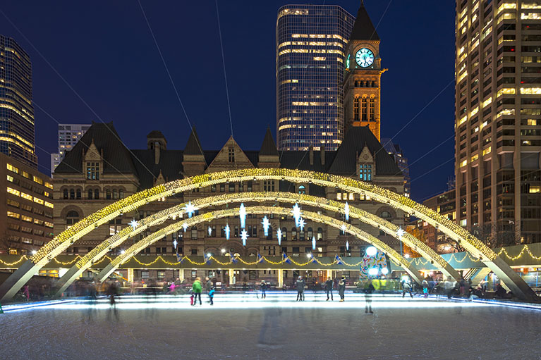 night view of ice rink of Nathan Philips square lit up with old city hall in background