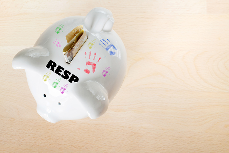 piggy bank with dollar bills in the slot with word RESP written on the piggy bank