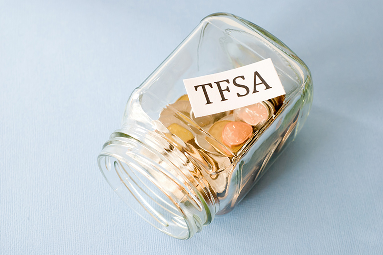 clear glass jar filled with coins tipped on it's side - labelled TFSA