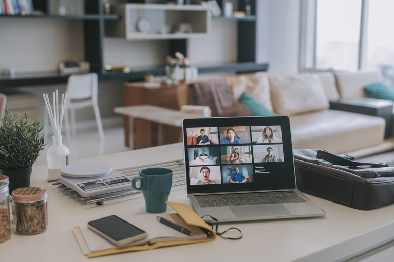 laptop on a desk in a home with screen showing virtual meeting