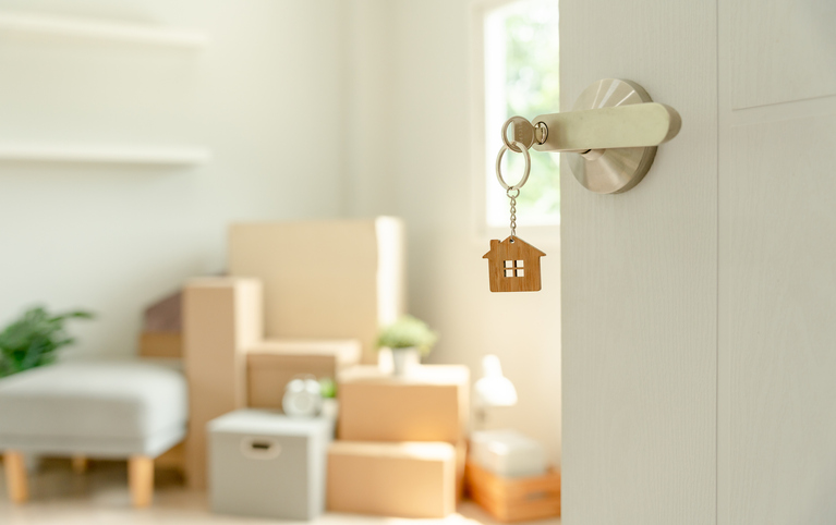 an open door with a house key showing a room with furniture an moving boxes
