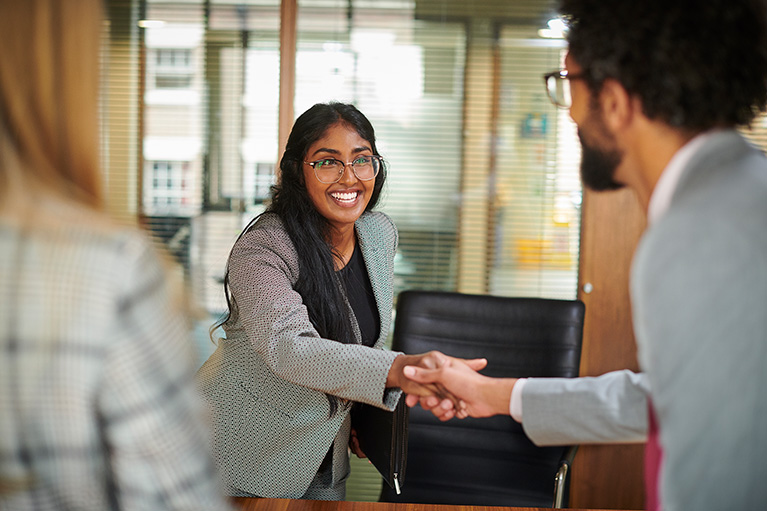 young woman shaking hands with a possible employer over a desk