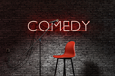 comedy club showing a chair and microphone with comedy lit up in back