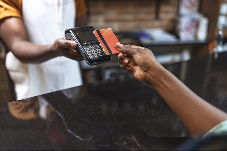 someone tapping their credit card on a pay machine at a restaurant