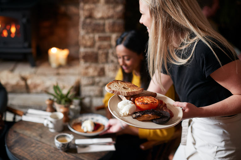 female waitress serving food to a table next to a fireplace
