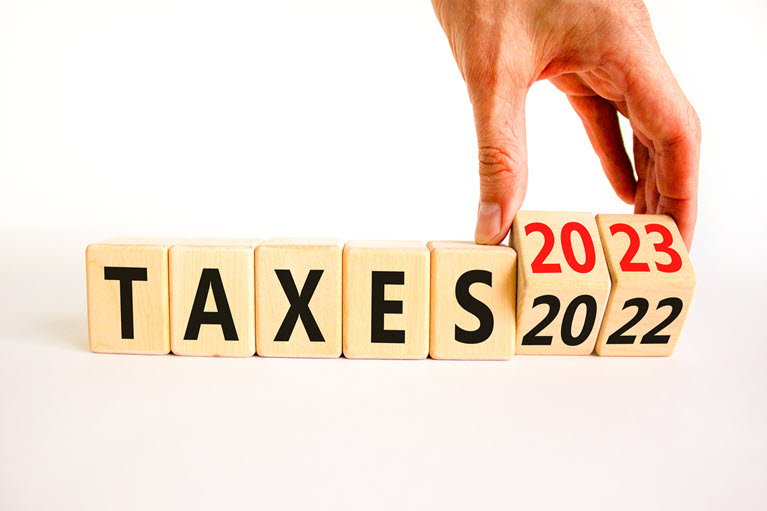 blocks with letters and numbers spelling out taxes 2023 with hand switching from 2022