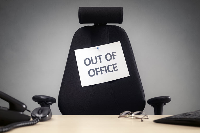 Black office chair with a sign posted saying "out of office"