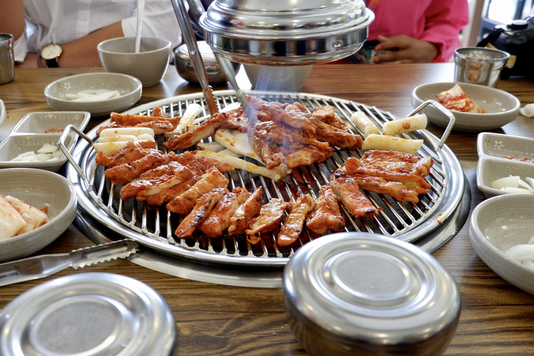 table showing a korean bbq meal with meat on the grill