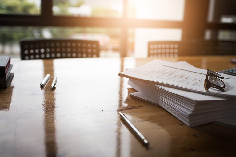 Pens and papers on a wooden table.