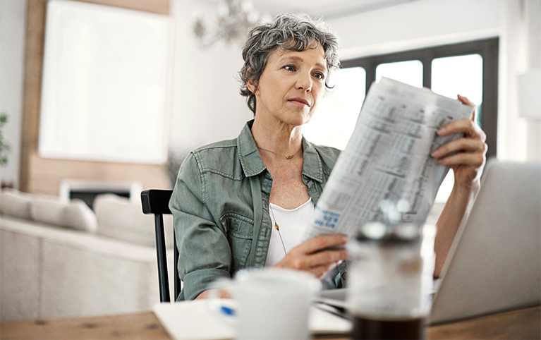 A woman reading an article about tax planning in the newspaper.