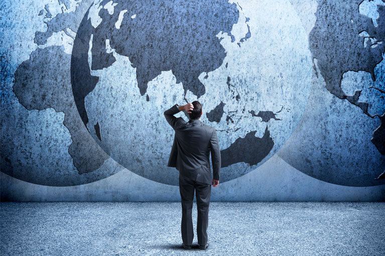 A man standing in front of a world map.
