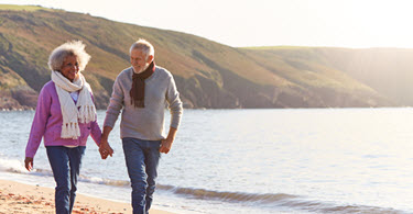 Happy retired couple walking on the beach