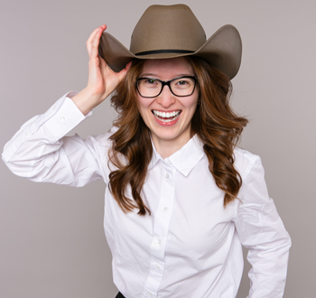 Alisa McNaughton (Jeff Wiebe Treasury Advisory Team) wearing a brown cowboy hat, holding the brim of the hat with one hand.