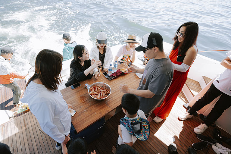 image of the team in the yacht gathered around the dining area eating shrimps.