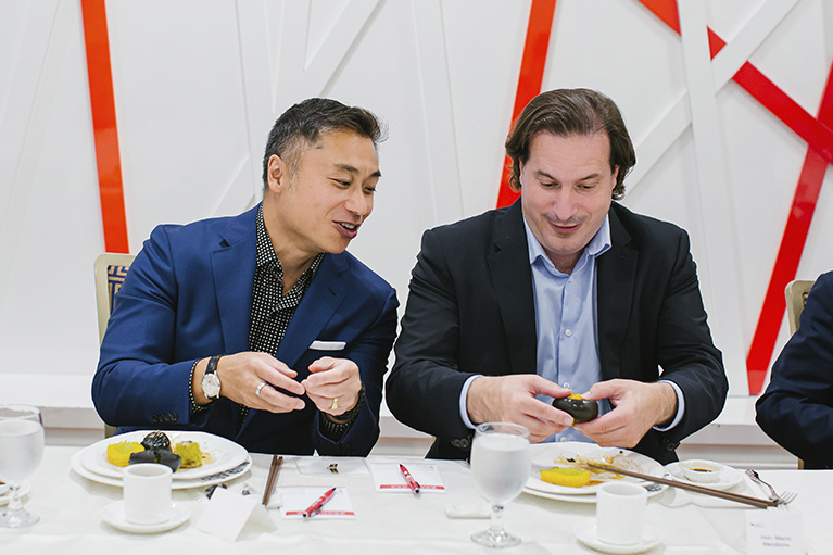 image of johnny cheung sitting and eating next to the minister of immigration marco mendicino.