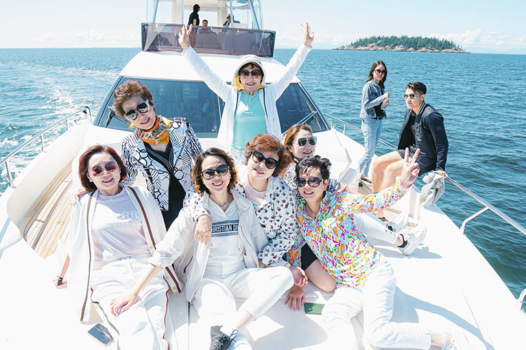 image of the team sitting in the yacht with their hands up.