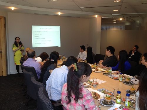A woman talking at the Sprott Shaw seminar in front of a large table.