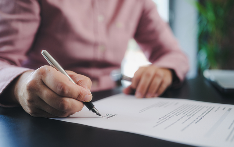 Image of a man signing over his estate planning documents.