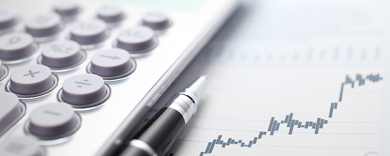 Calculator and ballpoint pen on stock market data chart.
