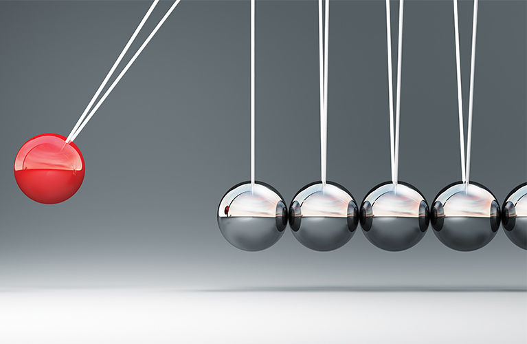 Silver chrome colored balls in a line and red ball that swing.