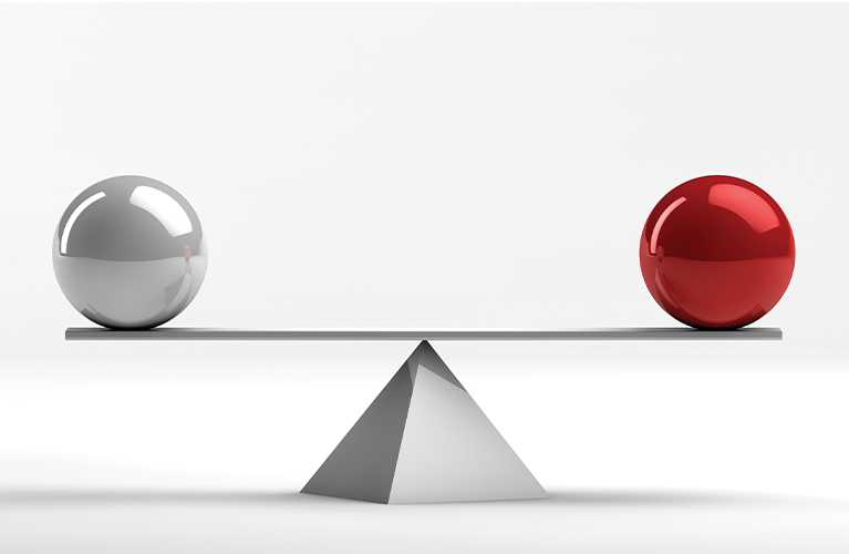 Chrome and red balls in perfect balance on a scale.
