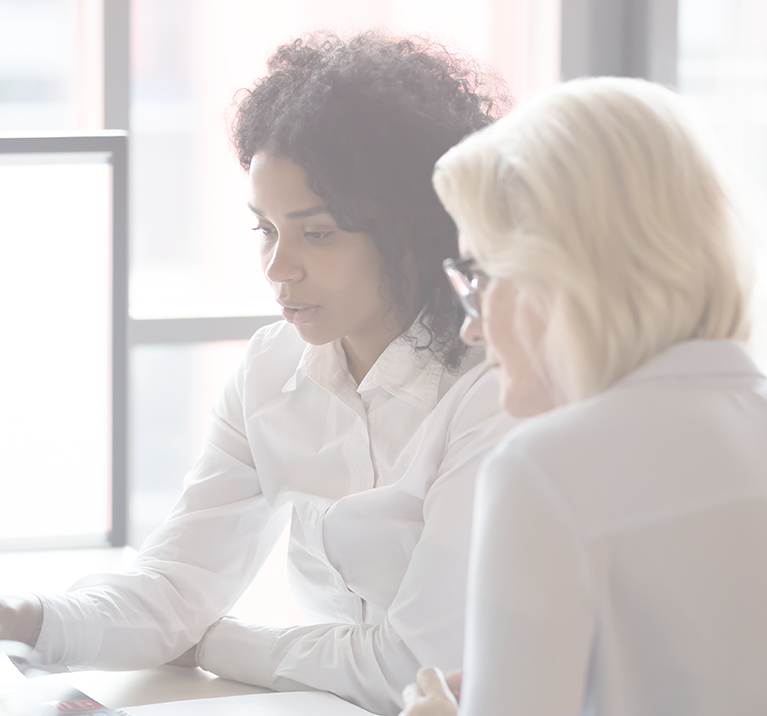 two women sitting next to each other and reviewing investment objectives