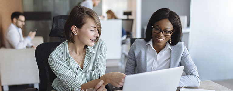 Two women looking at a computer screen, smiling.