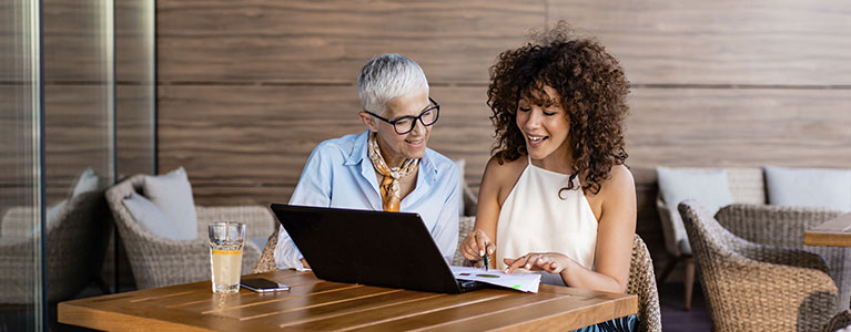 An older and a younger woman looking at computer laptop screen.
