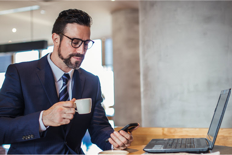 A man dressed in a suit looking at his mobile phone in an office