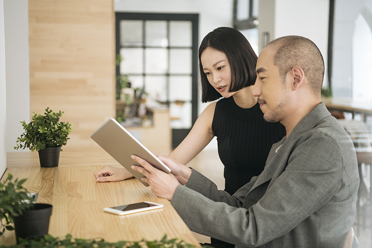 A man showing his female colleague something on a tablet in an office 
