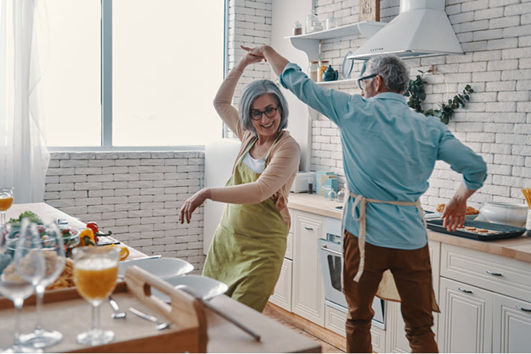 An older couple dancing in their kitchen.