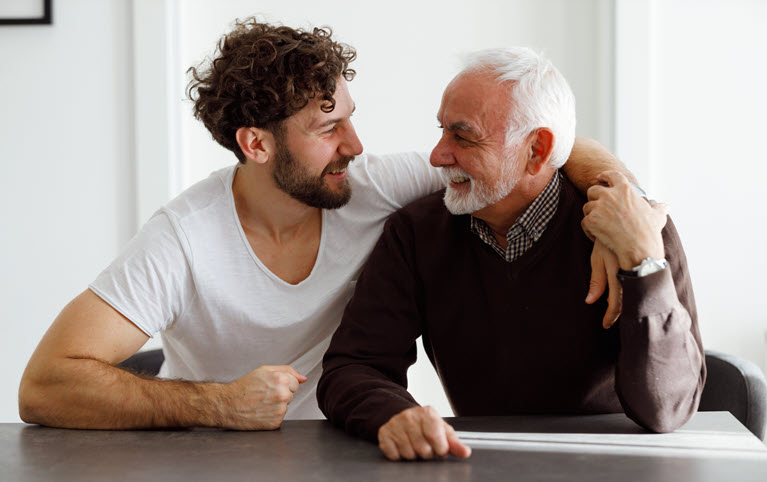 A son with his arm around his elderly father.