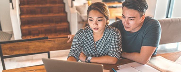 A man and woman looking at their finances on a laptop.