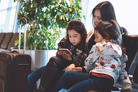 A woman and two childrens that look at a phone