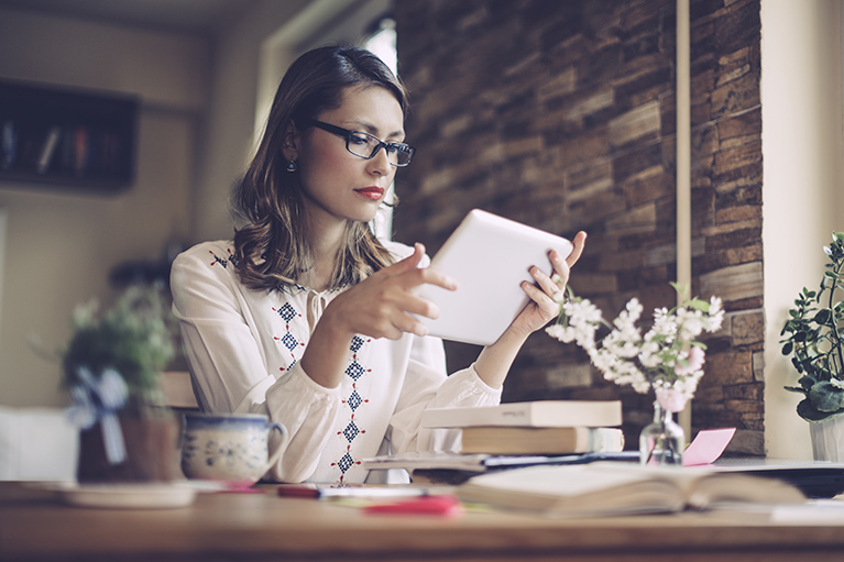 A woman reading an economic newsletter on her tablet.