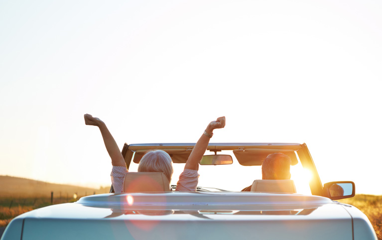 Retired couple in a convertible at sunset—symbolizing retirement income planning, estate strategy, and financial independence.
