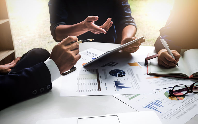 Three people sitting at a table reviewing their client's investment documents.