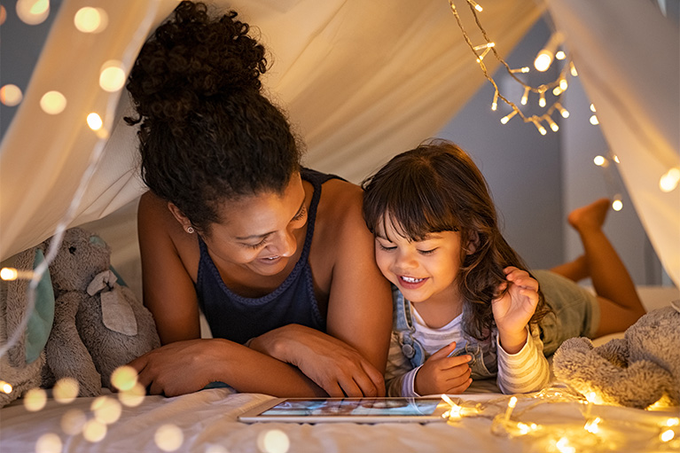A mother and her young daughter in a tent reading a story